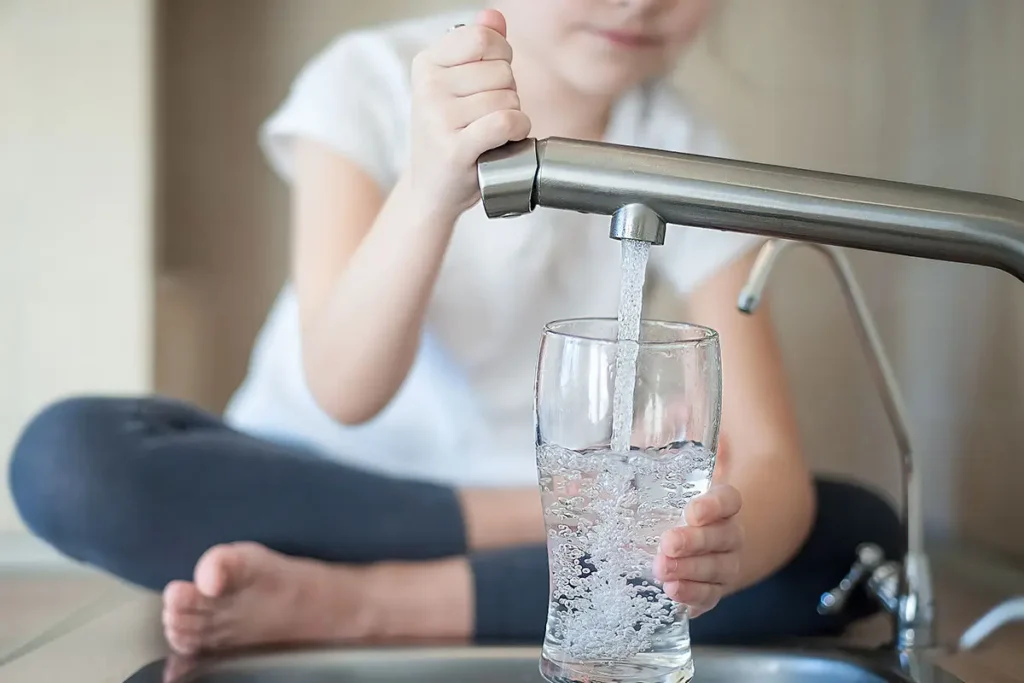 Little girl opens a water tap